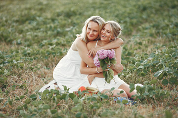 Fototapeta premium Adult mother with daughter. Beautiful girl in a white dress. Family in a summer field