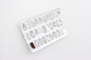 One last brown pharmaceutical pill in a used blister pack isolated on white