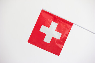 Small plastic Swiss national flag close up front shot isolated on white