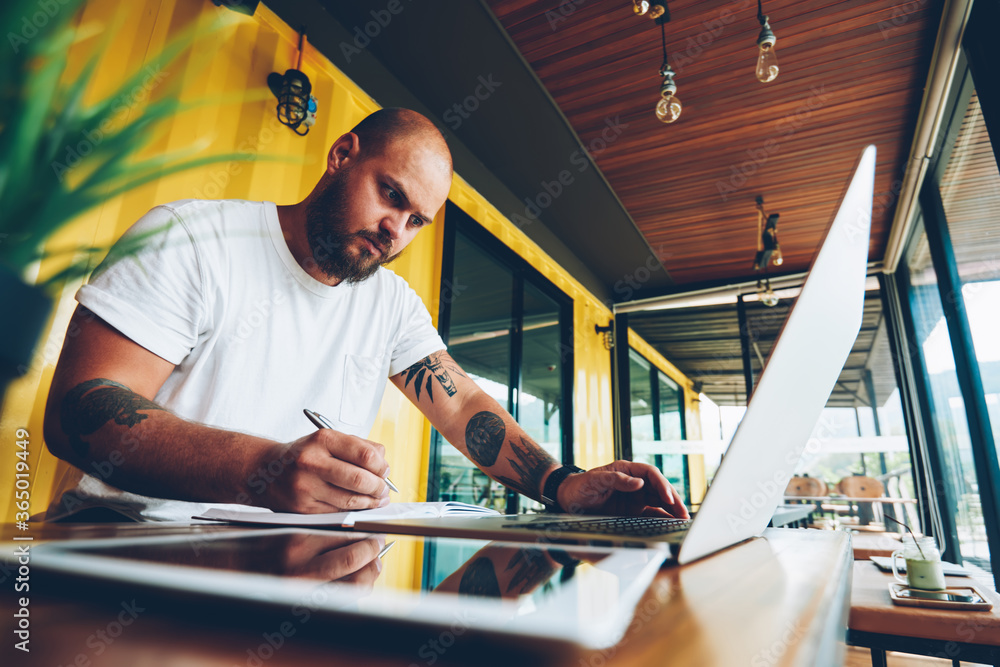 Poster skilled male blogger writing review for website analyzing information from networks via laptop compu