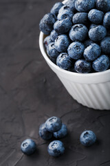 Organic blueberries in a white Cup on a black Board.