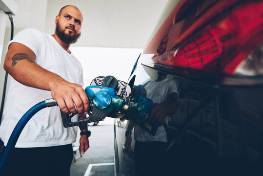 Serious Bearded Hipster Guy Filling Talk Of Automobile For Driving Holding Hose And Nozzle On Service Station,young Male Owner Of Car Refill Vehicle With Petroleum, Climate Pollution Concept.