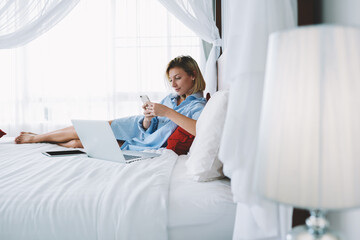 Attractive young woman sending message via smartphone chatting about business working on freelance...
