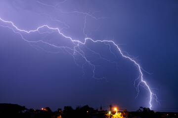 Lightning flashes in the night cloudy sky over the city. Storm.