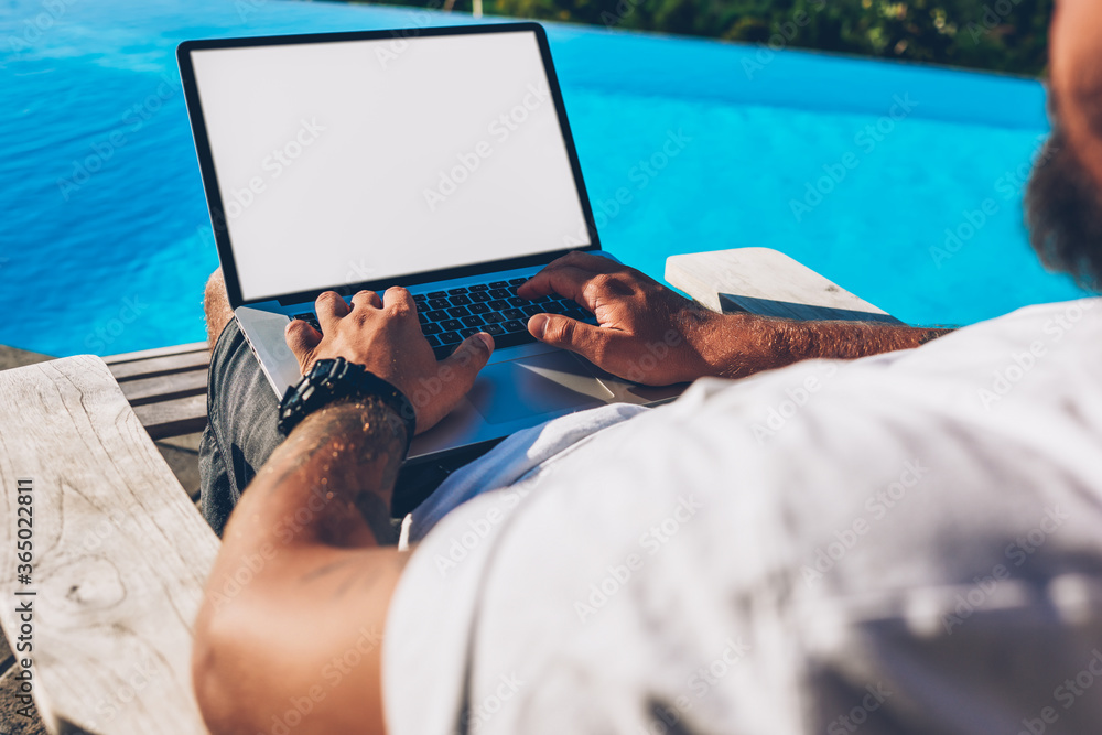 Poster cropped image of male hands typing text information on keyboard of modern laptop computer with blank