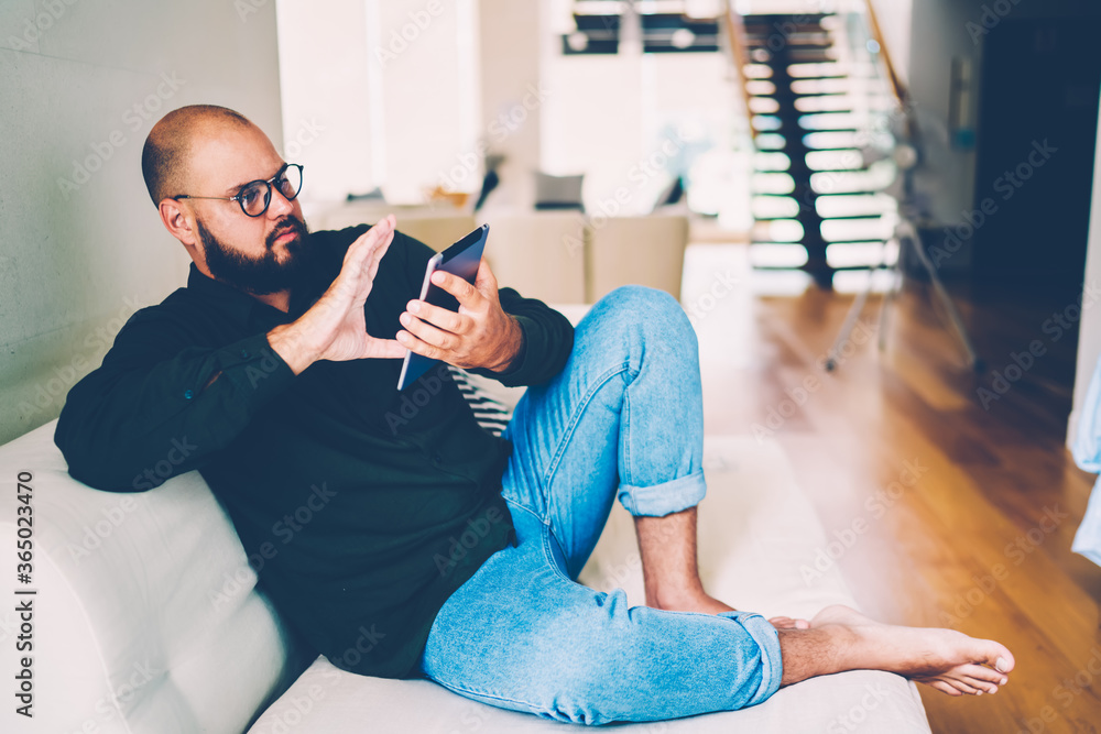 Poster handsome male in eyewear checking email via touchpad texting feedback using internet connection at h