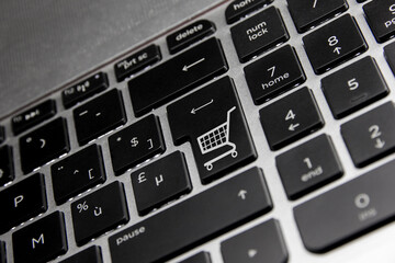 Online shopping, shown by a shopping icon on the Enter key of a minor reflective keyboard.