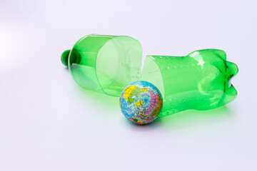 Plastic water green bottle cut in half, placed behind the blue globe. Concept of global warming and...