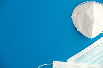 Covid-19 concept, protection and hygiene, 2 types of mask (surgical blue, kn959 white), turquoise background. Top view