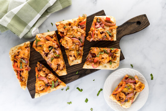 Applewood smoked BBQ shrimp flatbread pizza on a cutting board ready for eating.