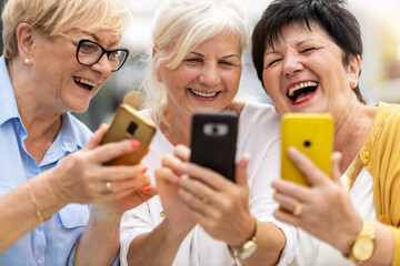 Group of senior women using smartphones together
