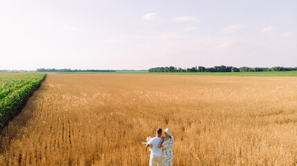 Family walks in wheat field near corn with baby.