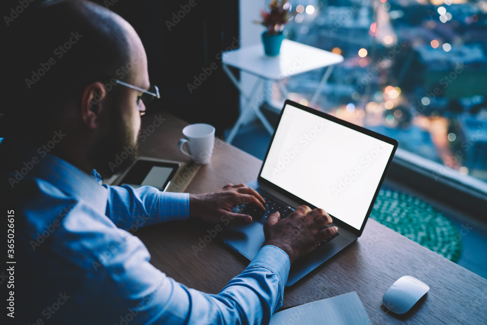 Poster businessman keyboarding on laptop computer with mock up screen working remotely on report, male entr
