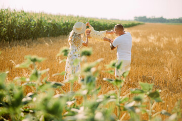 Family has fun and plays with their baby among wheat field.