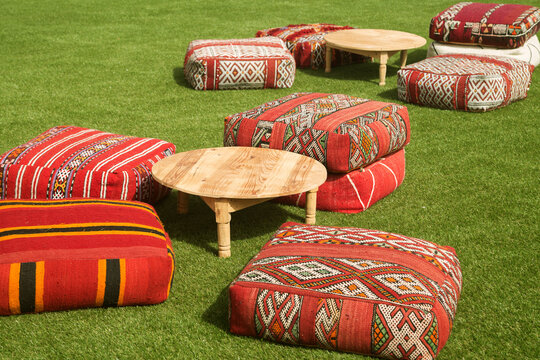 Moroccan decor on the lawn. Grass, a low table and traditional cushions and poufs