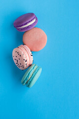 Close-up view of four colored French macaroons on a blue background. Sweet and colorful French macaroons. Dessert. Homemade sweets. Café dessert. Selective focus. Clipping path