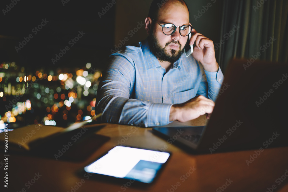 Poster skilled male working overtime on laptop computer consulting about software update with helpline oper