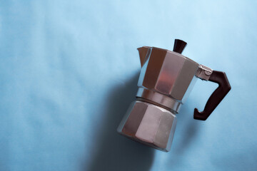 The geyser coffee maker lies on a blue background. With copy space.