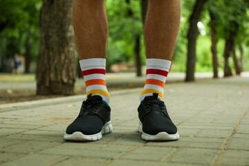 Fototapeta na wymiar Man in black sneakers and LGBT socks standing outdoor