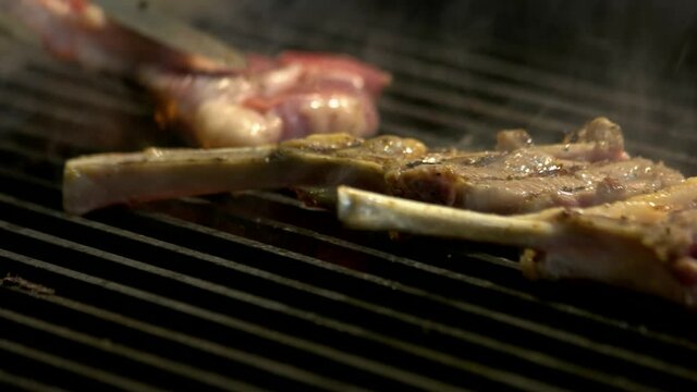 Chef grilling lamb ribs on flame. Chef cooking meat on the grill. Delicious dinner at restaurant.