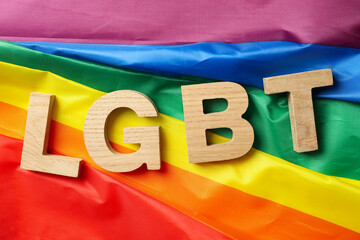 Wooden letters LGBT on LGBT flag, top view