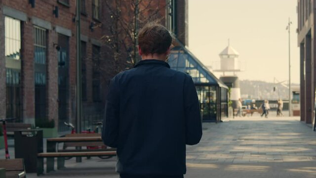 Young businessman looking on his phone while walking down a financial alley living a modern lifestyle in a growing city