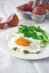 Fried eggs and rucola leaves on a white plate