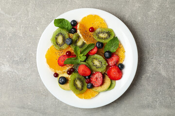 Plate of fresh fruit salad on gray background, top view