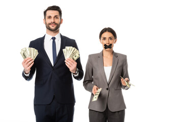 happy businessman holding dollars near businesswoman with duct tape on mouth isolated on white,...