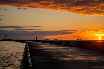 People enjoying beautiful sunset at the pier near the sea