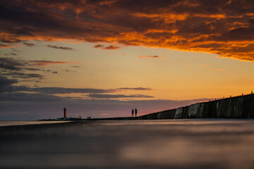 People enjoying beautiful sunset at the pier near the sea