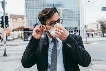 Business man standing or walking on city street with protective face mask. Virus epidemic concept.