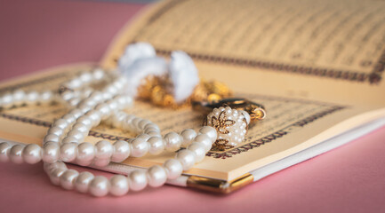 Holy Quran with tasbih or rosary beads. Ramadan concept with pink background