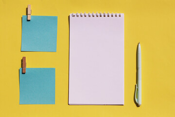 Flat lay leaflets for writing, a blank notebook on a spiral and a pen on a yellow background. Place for an inscription, top view