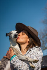 Woman love her dog. Pet owner kissing whippet