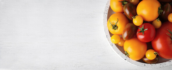 Top view of bowl with fresh tomatoes on white wooden table, space for text. Banner design