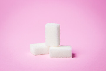 Sugar cubes on a pink background. Three sugar cubes lie on top of each other.