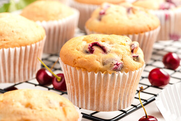 Closeup of homemade muffins with fresh cherry on a baking rack. Homemade cakes, sweet food.