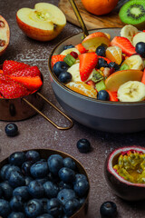 Bowl of fruit salad surrounded by fresh fruit
