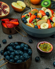 Bowl of fruit salad surrounded by freshly prepared fruit