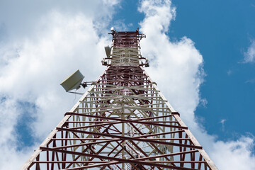 Cell tower with antennas on a blue sky background.