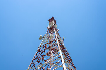 Cell tower with antennas on a blue sky background.