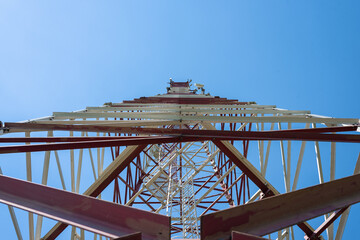 Cell tower with antennas on a blue sky background.