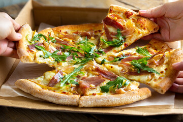 Pizza delivery to the office. Home-made pizza delivery. Pizza in the box. Party with fast food. Hands decorate slices of pizza. Hot fast food at home. Gathering friends with pizza. Party with food. 