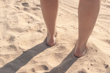 Fototapeta na wymiar Female legs in the beach sand