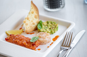 Fresh salmon, scallops and avocado tartar with lemon and bread close-up on a plate. horizontal