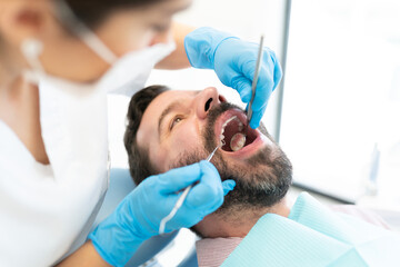 Dentist Checking Teeth Of Mid Adult Man