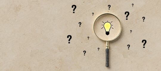 magnifying glass with lightbulb as symbol for finding a solution on paper background