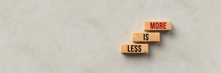 cubes with message LESS IS MORE on concrete background