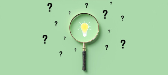 magnifying glass with lightbulb as symbol for finding a solution on light green background